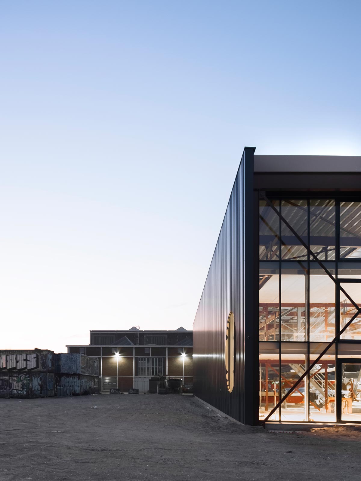 exterior dusk photo showing the office of Boat Hangar and the NDSM shipbuilding warehouse in the background by BETA architects Evert Klinkenberg Auguste Gus van Oppen