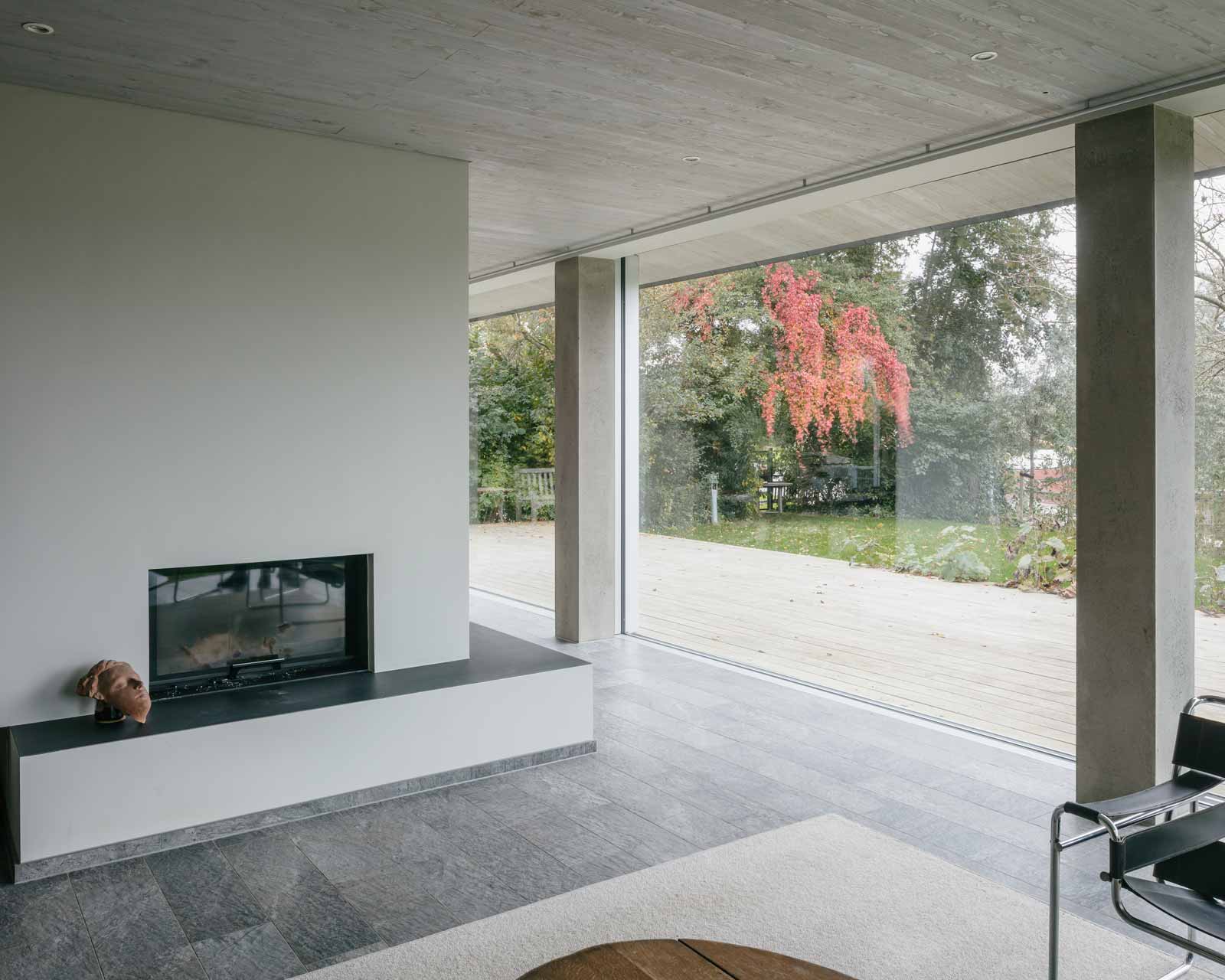 interior photo of house tc showing fireplace and large glass sliding doors by beta architect amsterdam evert klinkenberg gus auguste van oppen image by Stijn Bollaert